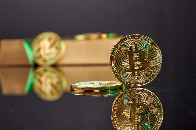 standing-bitcoin-coin-on-the-reflective-desk-2022-01-29-21-45-42-utc.jpg